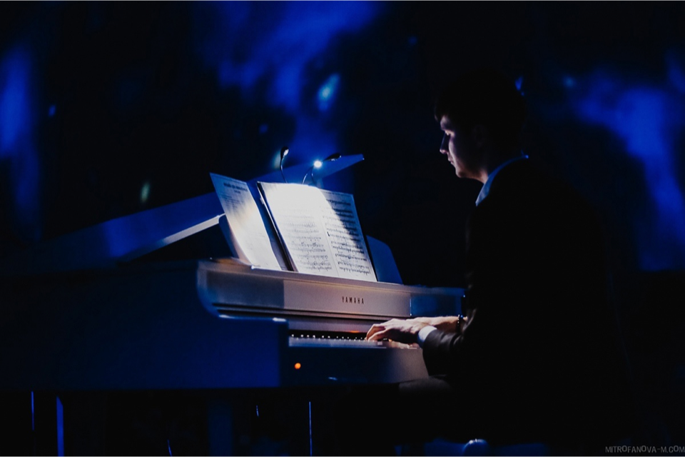 Pianist speelt op een vleugel in blauw licht in Vincent Hall