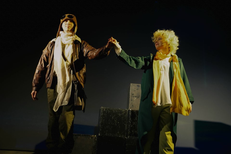 The Pilot and the Little Prince holding hands on stage