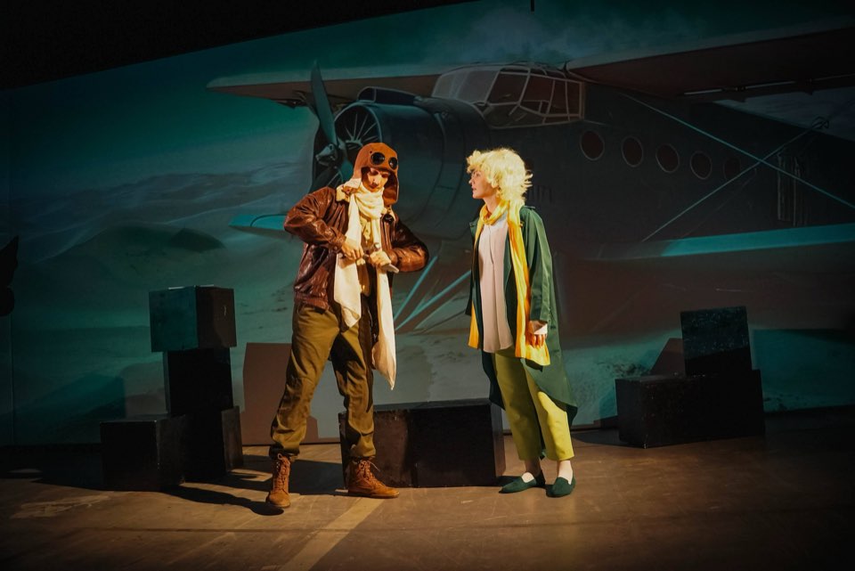 The Pilot and the Little Prince on stage in front of a projected aeroplane